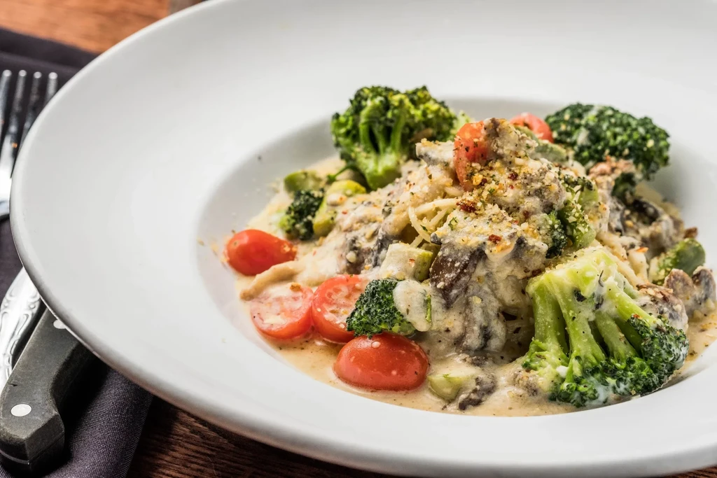 Creamy pasta with broccoli, tomatoes, mushrooms, and a coarse topping.