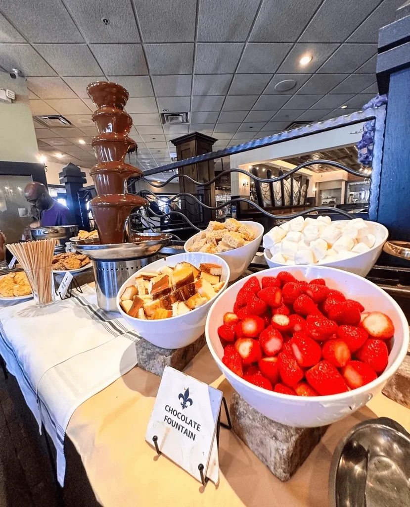 Chocolate fountain with strawberries, marshmallows, and cake at a buffet.
