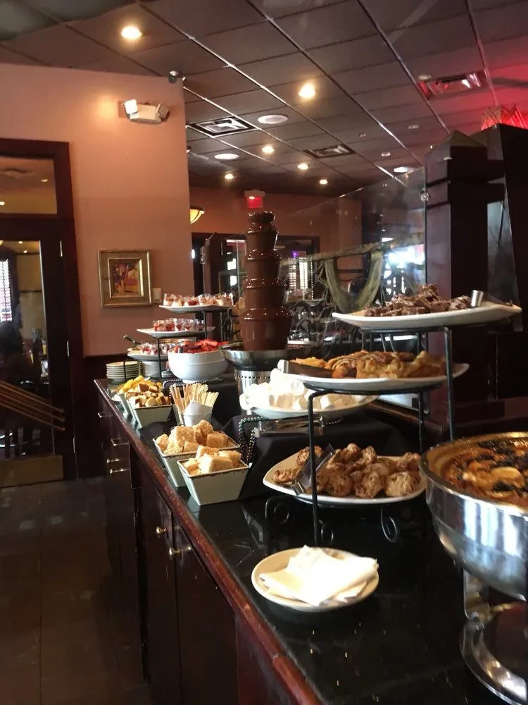 Dessert buffet featuring a multi-tiered chocolate fountain, pastries, and parfaits.