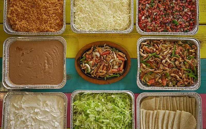 Overhead view of fajita platter, rice, beans, tortillas and toppings