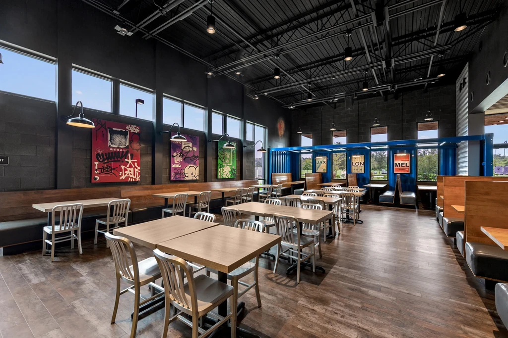 Empty modern restaurant with blue shipping container nooks and street art.