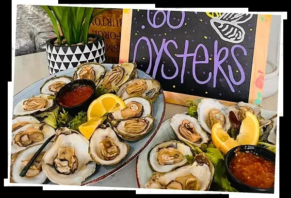 Two platters of fresh oysters on half shell with lemon and sauce.