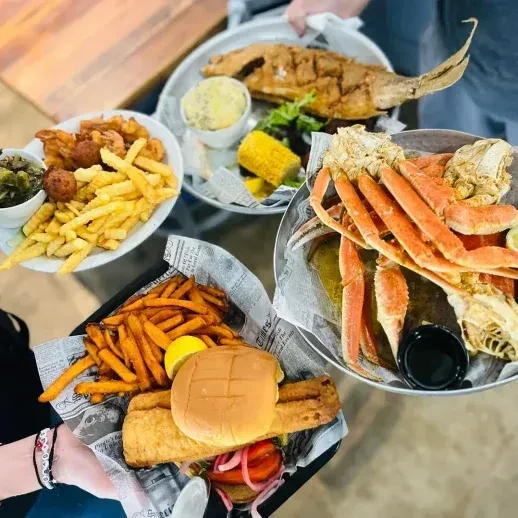 Overhead view of multiple plates of fried seafood and sides.