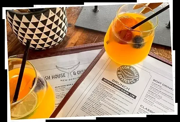 Amber drinks with fruit garnishes and menus on a wooden table.