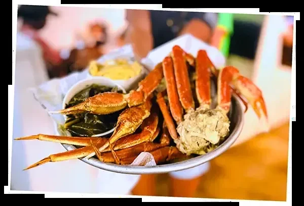 Platter with cooked snow crab legs, collard greens, and macaroni and cheese.