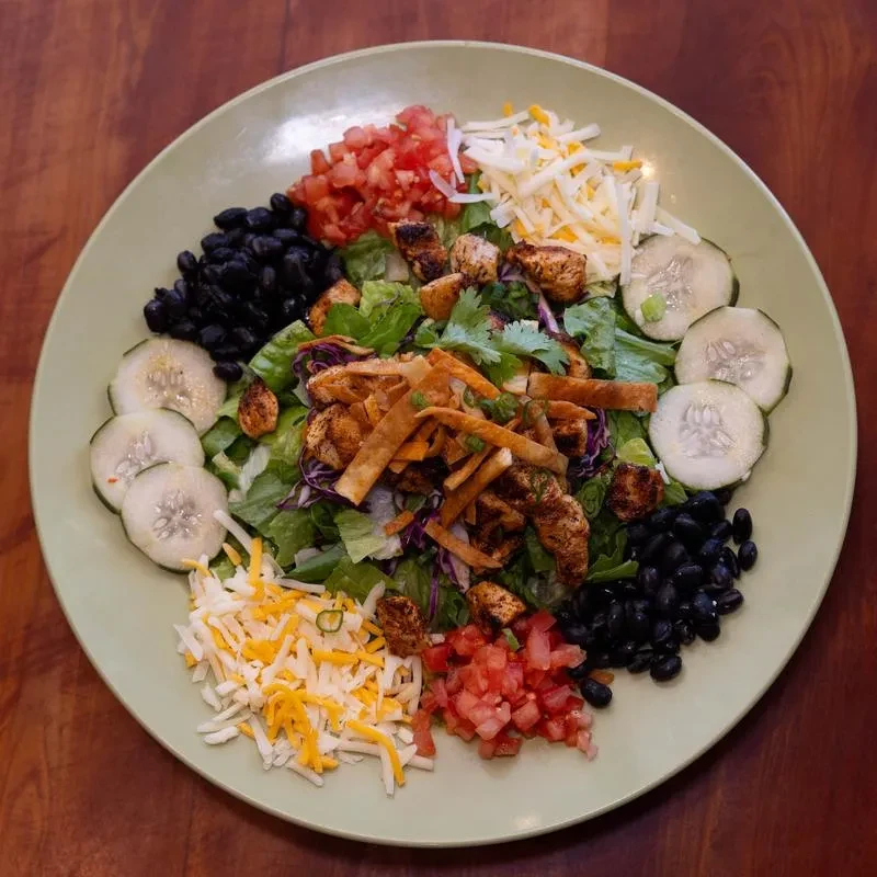 Grilled chicken salad with mixed greens, tortilla strips, beans, and cheese.