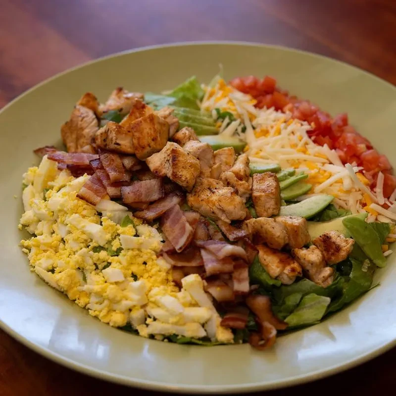 Cobb salad with chicken, bacon, egg, cheese, tomato, and avocado.