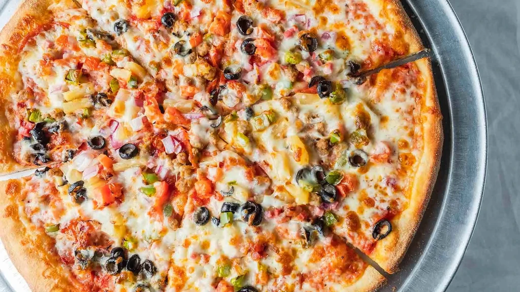 Close-up of a vibrant, multi-topped pizza with one slice cut.