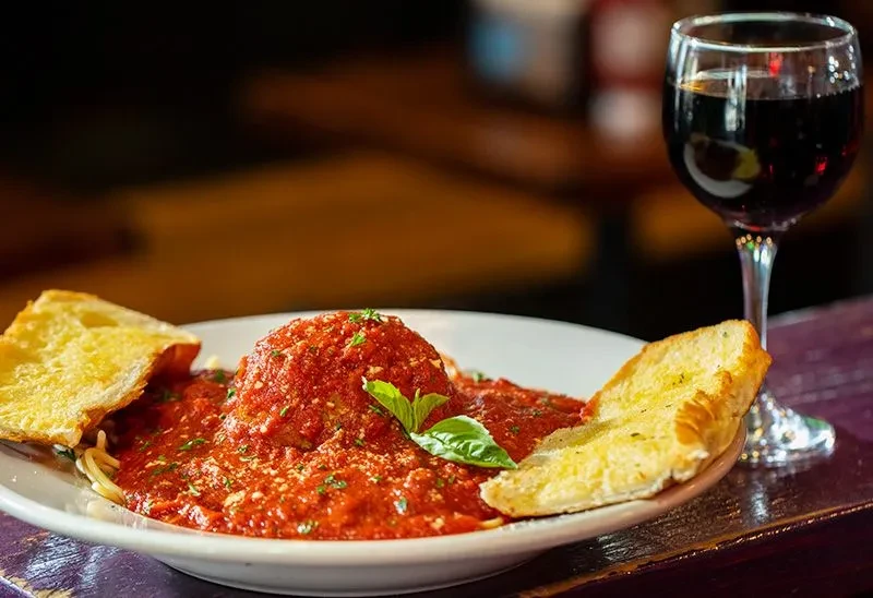 Spaghetti with meatball, basil, parmesan, garlic bread, and red wine.