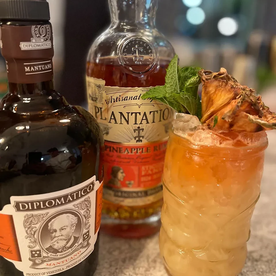 Diplomatico and Plantation rum bottles with a pineapple and mint cocktail.