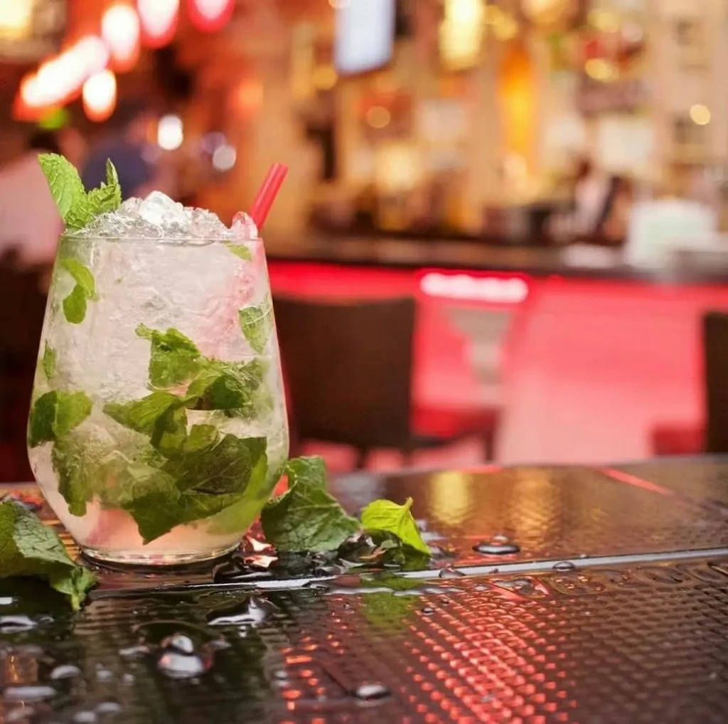 Close-up of frosty mojito with crushed ice, fresh mint, red straw.