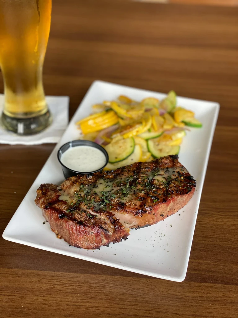 Grilled steak, sautéed vegetables, dipping sauce, and beer.