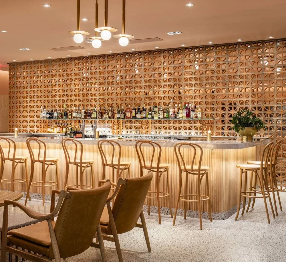 Empty modern-retro bar with a curving counter and patterned terracotta wall.