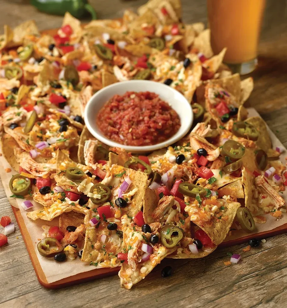 Loaded nachos platter with melted cheese, chicken, jalapeños, and salsa.