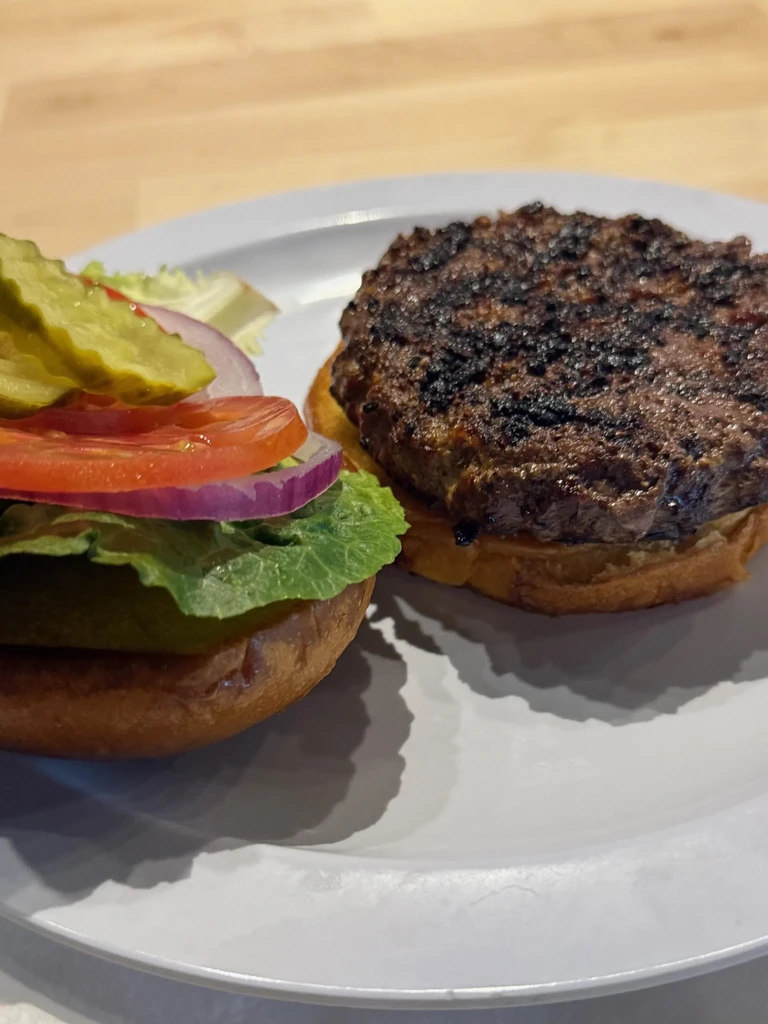 Deconstructed hamburger: grilled patty, bun halves, lettuce, onion, tomato, pickles.