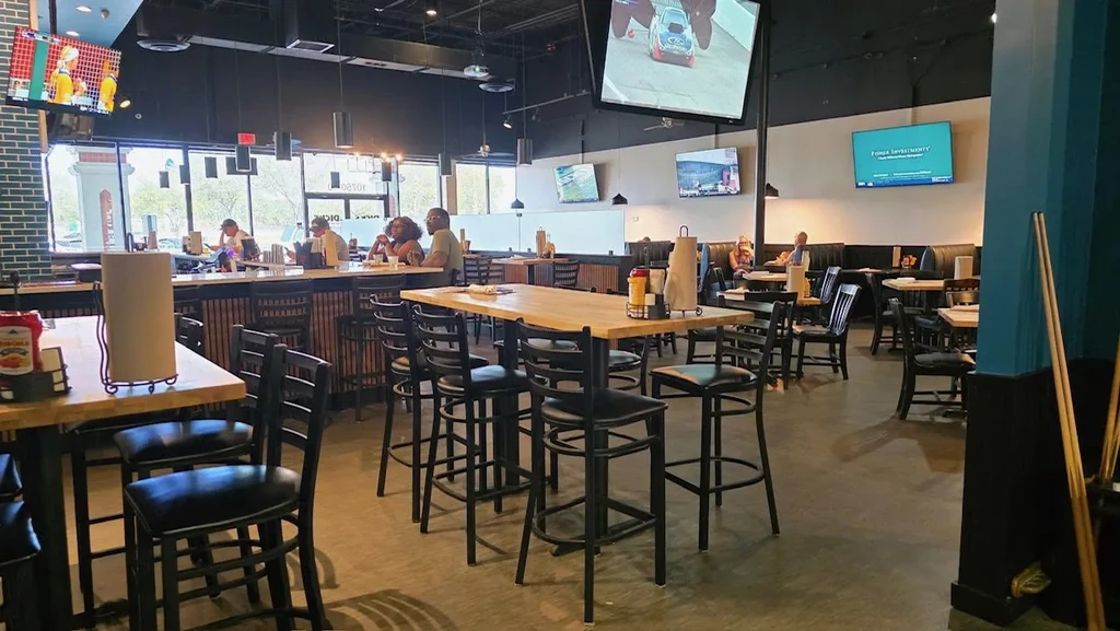 Interior of a spacious casual sports bar with multiple TVs and patrons.
