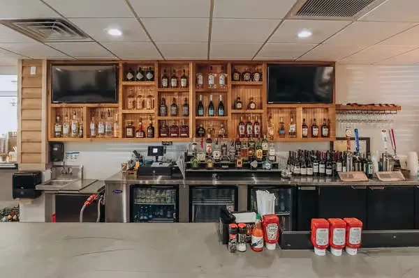 Clean, well-stocked bar with liquor bottles, beer taps, and televisions.