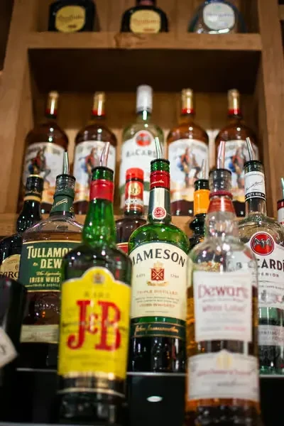 Numerous bottles of various spirits on wooden bar shelves.