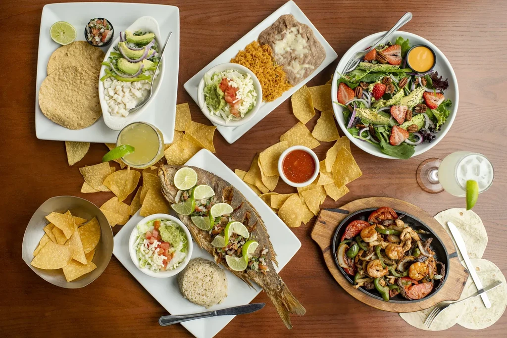 Abundant overhead spread of diverse Mexican dishes and margaritas.