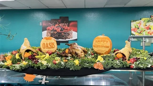 Lavish Thanksgiving buffet with roasted turkey, fruits, cornucopias, and carved pumpkins.