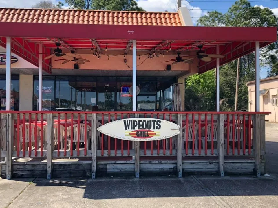 WIPEOUTS GRILL exterior with red roof, awning, and outdoor patio.