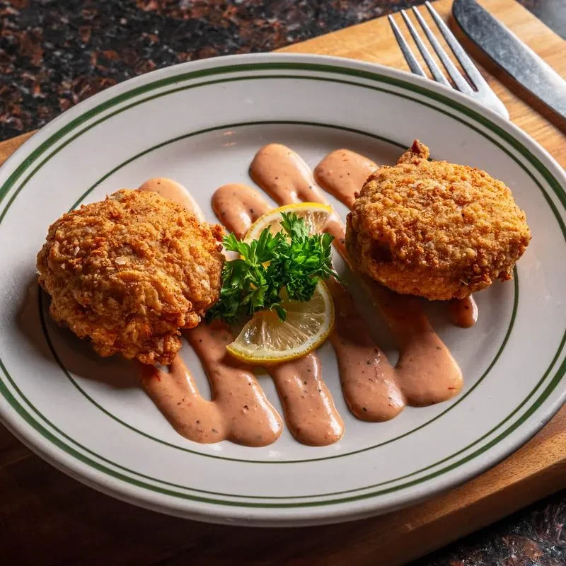 Two golden-brown fried patties with sauce, parsley, and lemon.