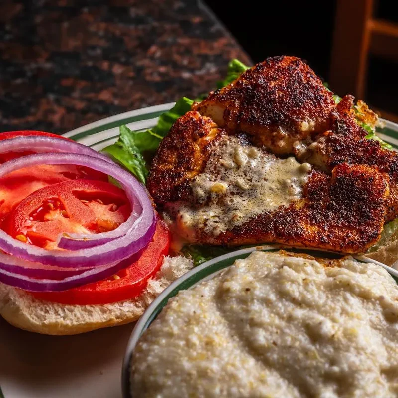 Close-up: Seasoned open-faced burger with lettuce, tomato, onion, and creamy side.