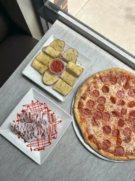 Overhead view of pizza, garlic bread, and powdered sugar fried dough.