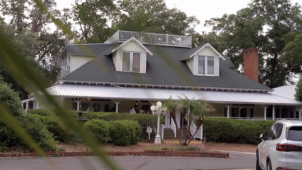 Historic restaurant building with a white wrap-around porch and green roof.