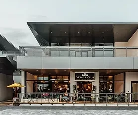 Modern building with Oaxaca Club restaurant and outdoor seating.