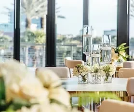 Elegant dining table with white flowers, glass decor, bright window view.