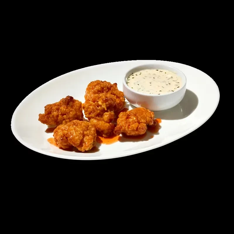 Five sauced fried chicken pieces with dip on a white plate.