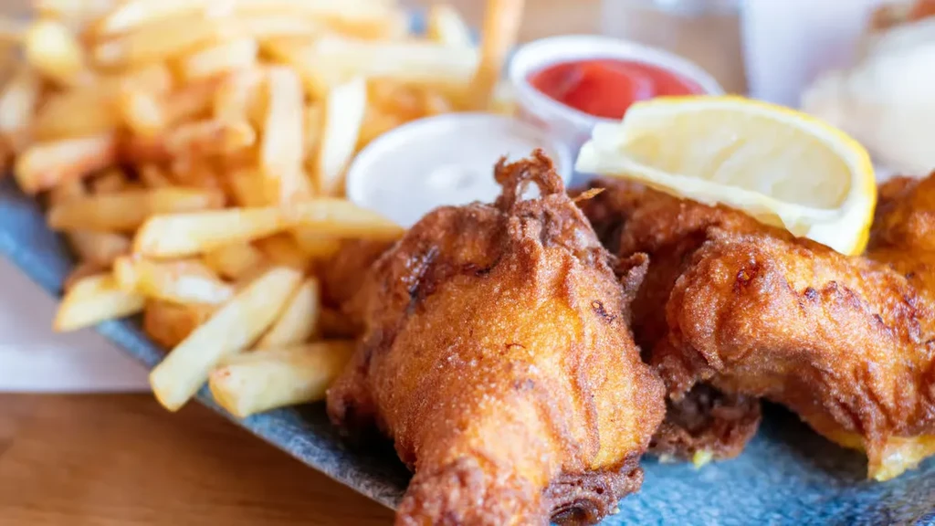 Crispy fried chicken or fish with french fries, lemon, and sauces.