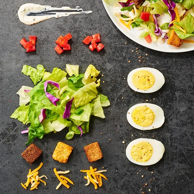 Flat-lay of arranged salad ingredients and a small mixed salad.