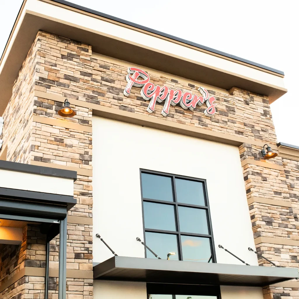 Multi-layered Pepper's restaurant facade with stacked stone and a lit sign.