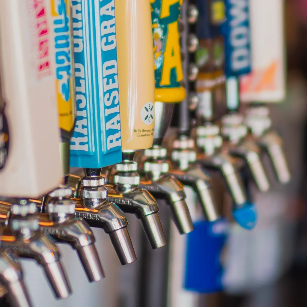Close-up of several colorful beer tap handles and spouts.