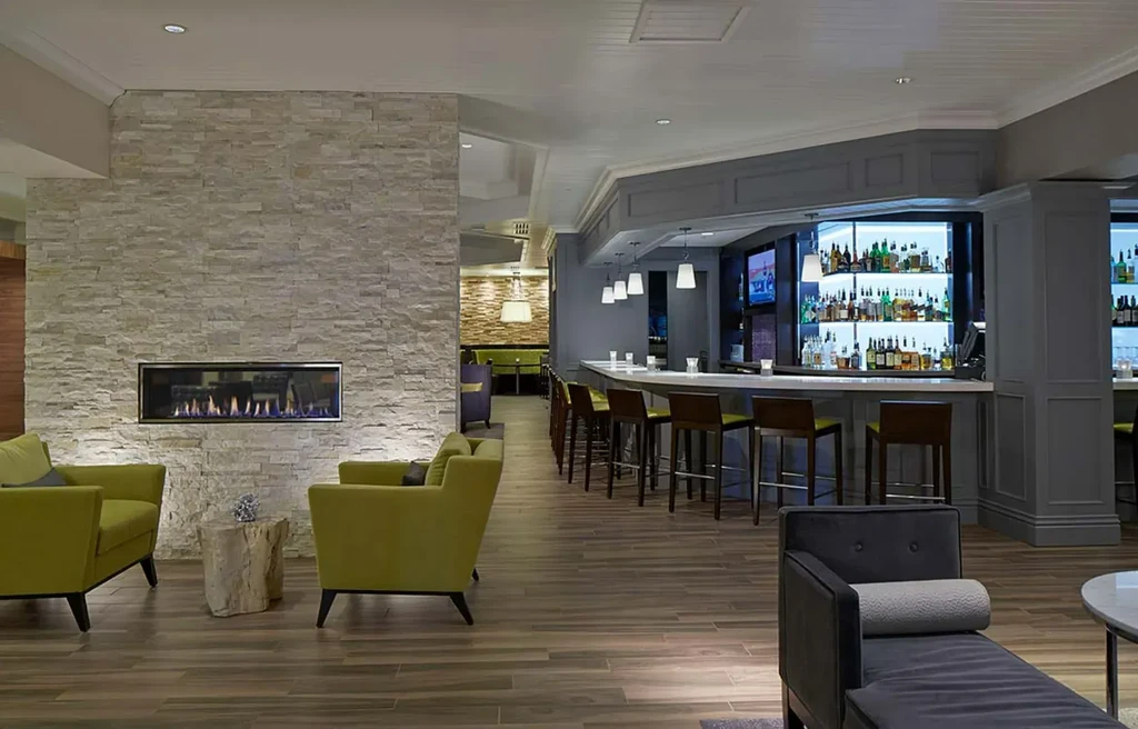 Modern lounge and bar with a stone fireplace and illuminated liquor shelves.