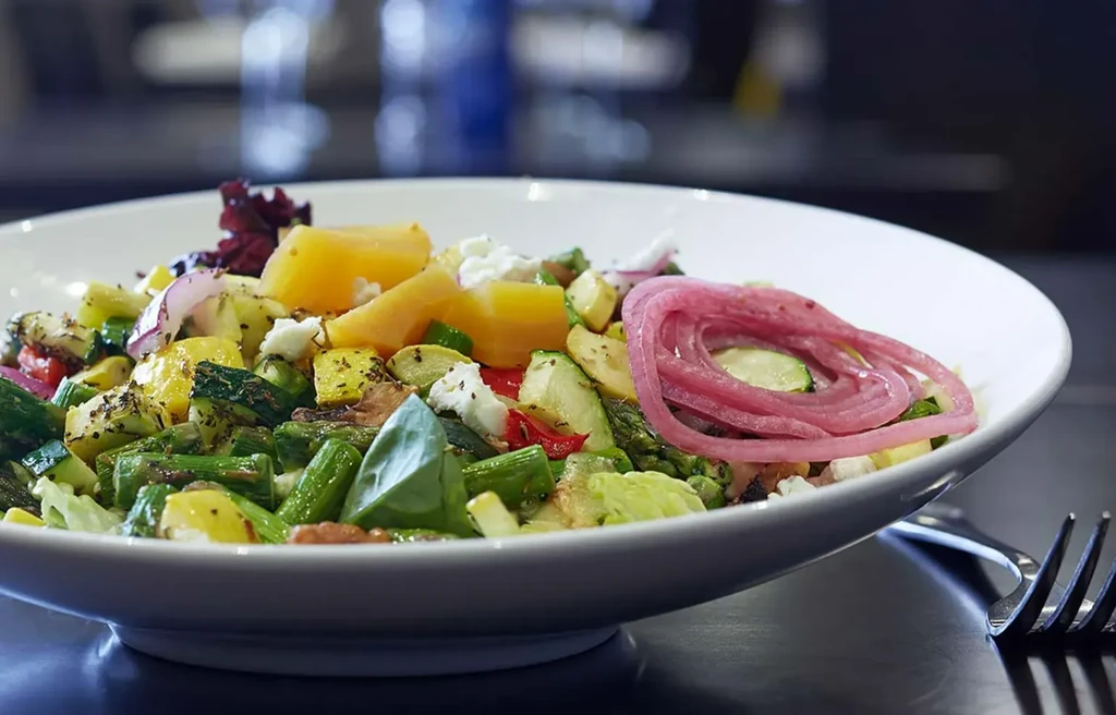 Colorful salad with asparagus, zucchini, feta, and pink pickled onions.