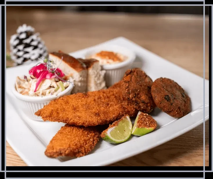 Platter of fried fish/chicken, falafel, coleslaw, dips, lime, and toast.