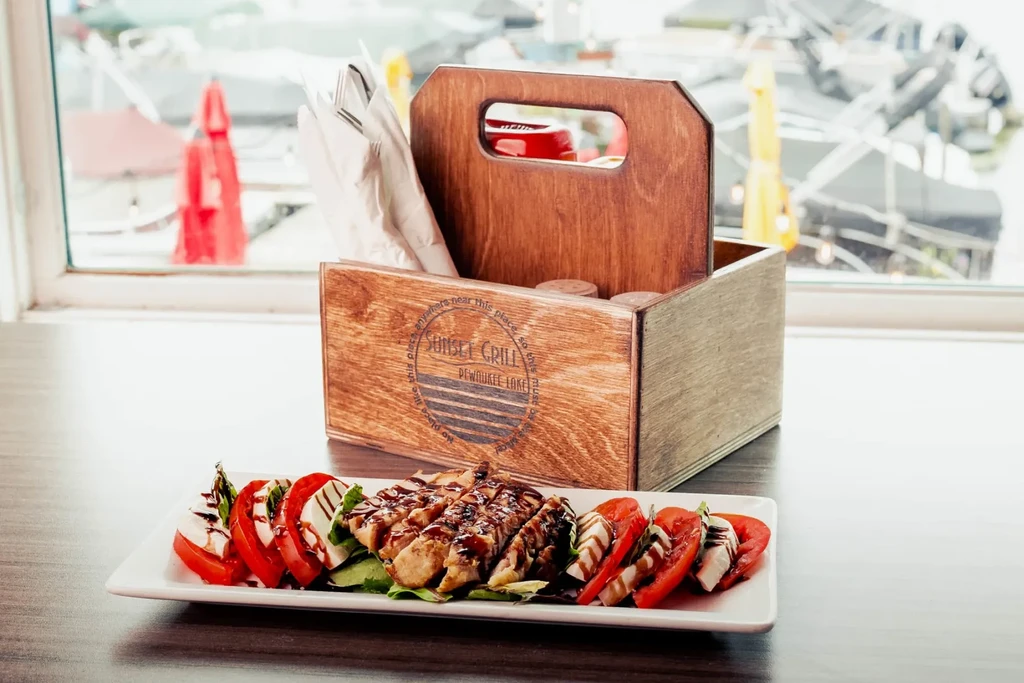 Grilled chicken and Caprese salad on platter with lakeside Sunset Grill.