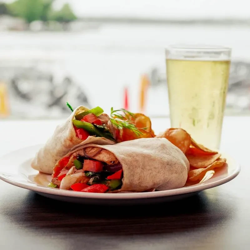 Grilled protein and vegetable wraps, potato chips, and drink.