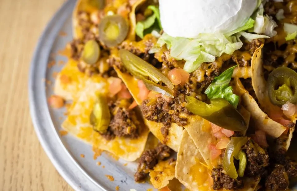 Nachos with ground meat, cheese, jalapeños, and vegetable toppings.