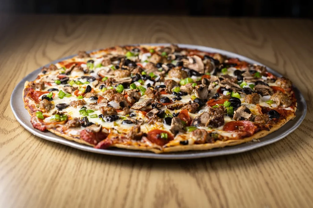 Round pizza with pepperoni, sausage, mushrooms, olives, and cheese.