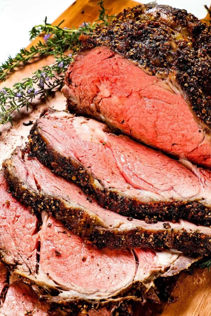 Spice-rubbed beef roast, sliced medium-rare, on board with herbs.