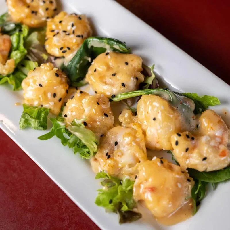 Fried shrimp in creamy orange sauce, lettuce, and sesame seeds.