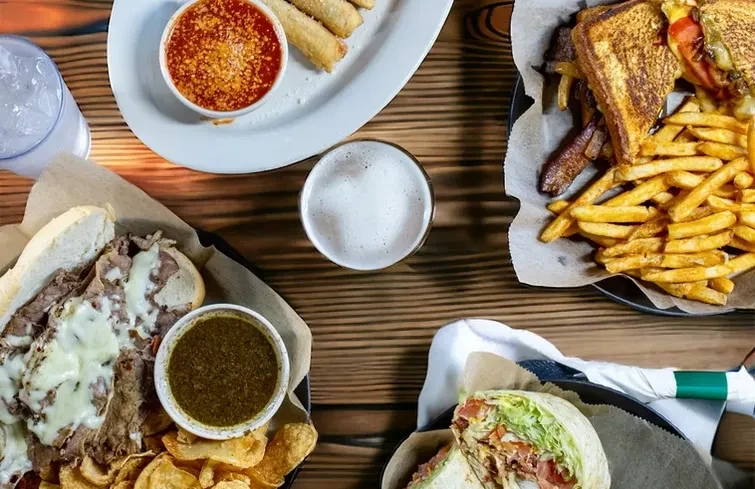 Overhead shot of casual restaurant food and drinks on a rustic table.