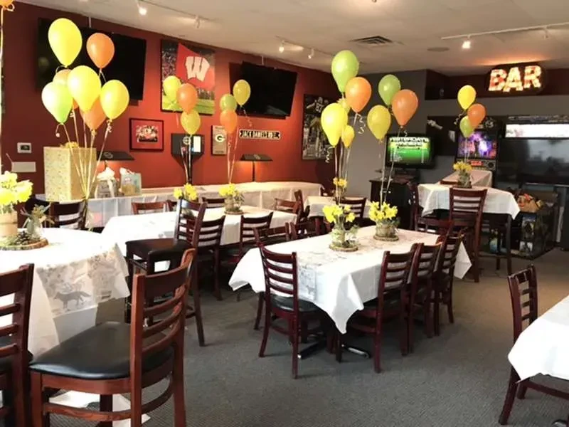 Bar interior set for an event with balloons, flowers, and sports decor.