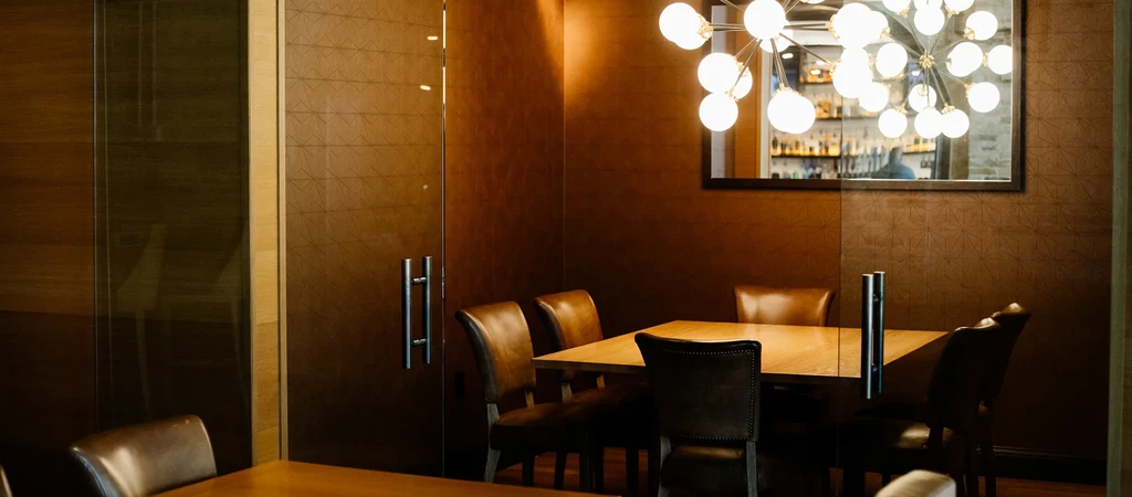 Upscale private dining room with wooden table, leather chairs, and mirrored bar.