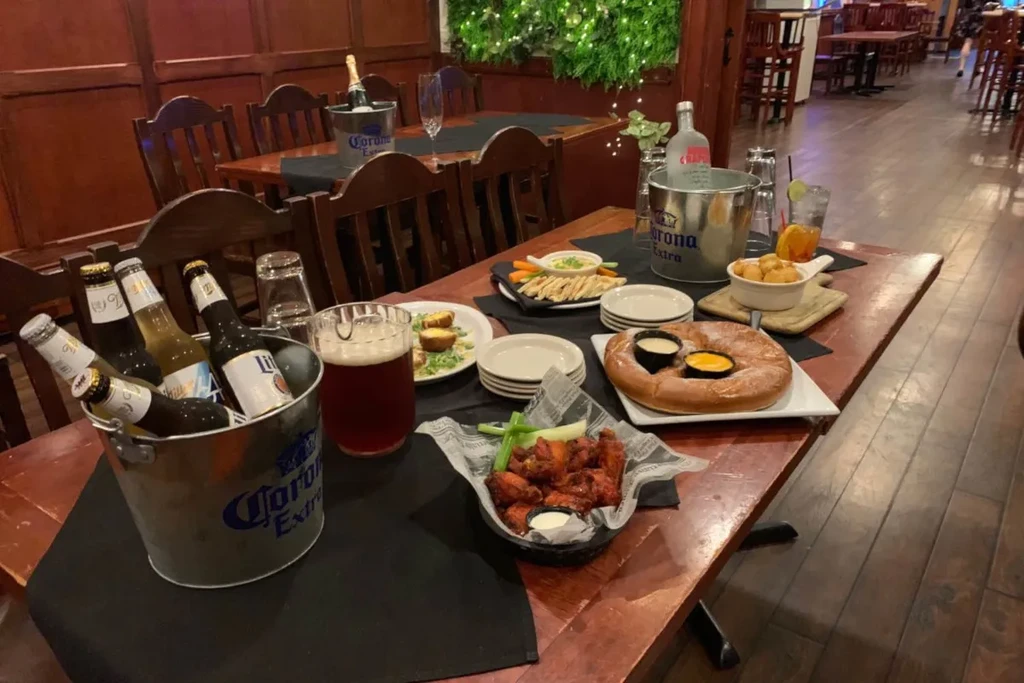 Restaurant table with drink buckets, buffalo wings, pretzel, and appetizers.