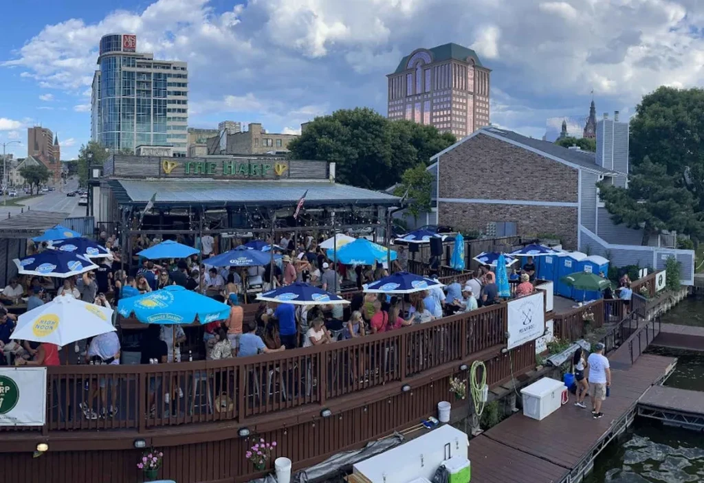 The Harp restaurant's bustling waterfront patio with city skyline.